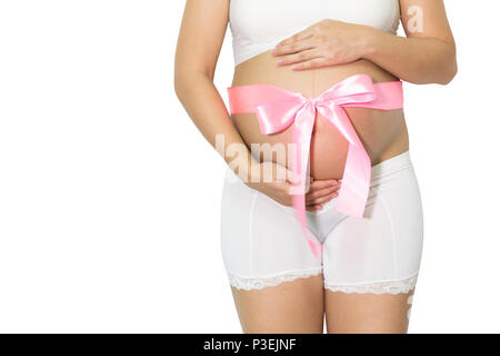 Donna incinta mani ventre con nastro rosa dono sulla pancia, figlia sano concetto, con copia spazio isolato sullo sfondo bianco. Foto Stock