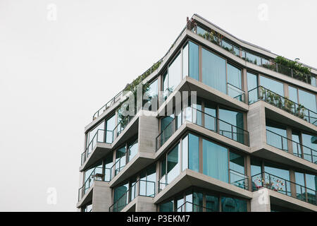 L'angolo dell'edificio con molte finestre contro il cielo grigio Foto Stock