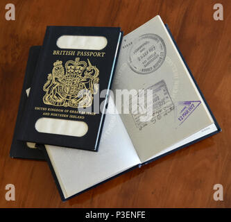 Blu passaporti britannici con una aperta con entrata e uscita timbri illustrato sulla antica scrivania Foto Stock