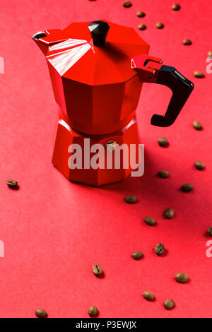 Red macchina per il caffè e il caffè in grani su sfondo rosso. Macchina da caffè espresso. Foto Stock
