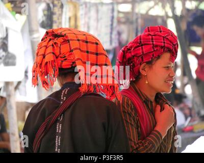 In prossimità dei due giovani sorridenti Shan ragazze in rosso e arancione controllato di acconciatura tradizionali nel mercato vicino Lago Inle, Myanmar (Birmania) Foto Stock