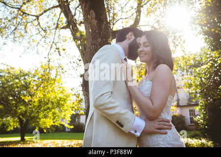 Sorridente sposa e lo sposo abbracciando in giardino Foto Stock