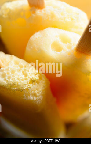 Close up (macro) di giallo ananas lollies ghiacciata (popsicles) con bastoni di legno. Foto Stock