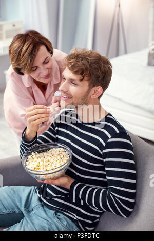 Gioioso uomo positivo mangiare popcorn Foto Stock