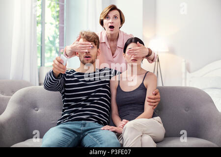 Emotivo piacevole donna in piedi dietro il giovane Foto Stock
