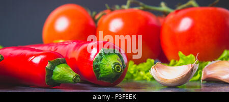 Peperoncino rosso, pomodori, Sadat e aglio su un marmo grigio sfondo Foto Stock