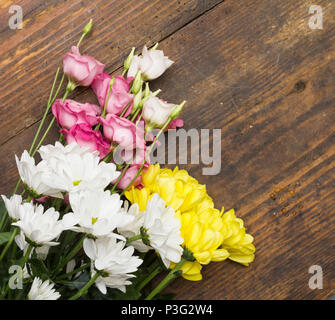 Crisantemo e fiori Eustoma disposte come una immagine naturale sul vecchio invecchiato in legno marrone weathered sfondo con soft bianca rosa e fiori di colore giallo, Foto Stock