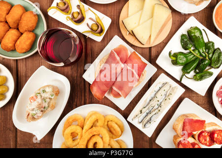La cucina di Spagna. Una foto aerea di varie tapas spagnoli, ripresa dall'alto su un rustico scuro texture. Jamon, formaggio, vino, olive, crocchette, cala Foto Stock