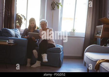 Donna Senior e figlia utilizzando una linguetta mentre si posa sul divano Foto Stock