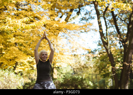 Senior donna a praticare yoga in un parco Foto Stock