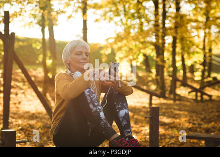 Senior donna utilizzando il suo telefono cellulare nel parco Foto Stock