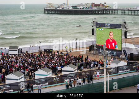 Brighton, East Sussex. Il 18 giugno 2018. Per gli appassionati di calcio guarda Inghilterra di apertura della coppa del mondo di gioco contro la Tunisia a Brighton il aria aperta Luna Beach cinema schermo sul lungomare di Brighton. Qui illustrato, Harry Kane, Inghilterra del capitano di una squadra celebra il traguardo di apertura della coppa del mondo campagna in Russia, come i tifosi di calcio festeggiare davanti al grande schermo. Credito: Francesca Moore/Alamy Live News Foto Stock