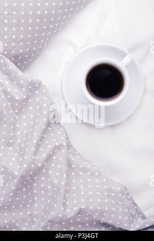 La tazza di caffè sul letto grigio. Vista superiore, mattina concetto dell'umore. Foto Stock