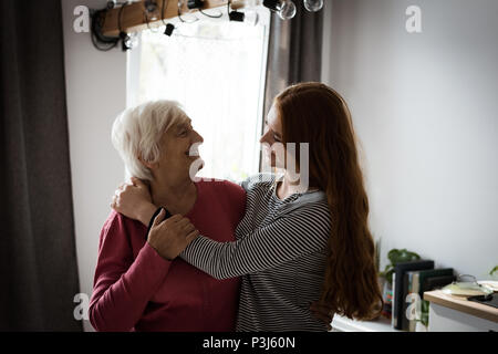 Nonna e grand figlia che abbraccia ogni altro in salotto Foto Stock