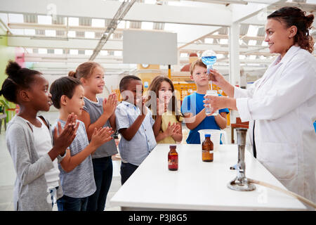 Tecnico di laboratorio che mostra entusiasti kids un esperimento scientifico Foto Stock