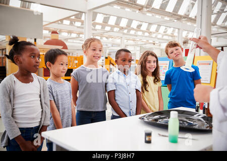 Tecnico di laboratorio che mostra il cilindro graduato per un gruppo di bambini Foto Stock