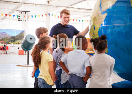 Ragazzi delle scuole guardando un gigantesco globo in un centro scientifico Foto Stock