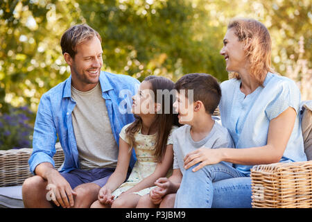 Bianco giovane famiglia seduti insieme in giardino Foto Stock