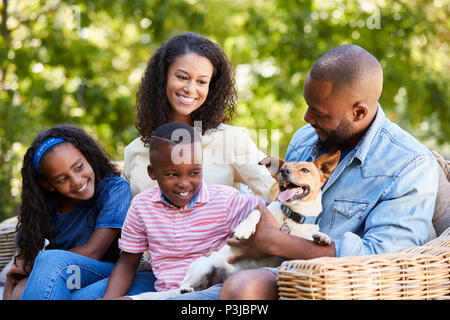 I genitori e i due bambini seduti con il cane in giardino Foto Stock