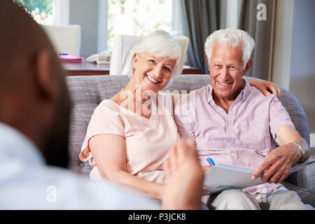 Felice coppia senior tenendo la consulenza finanziaria a casa Foto Stock