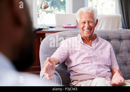 Felice l'uomo senior tenendo la consulenza finanziaria a casa Foto Stock