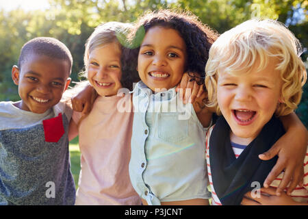 Quattro bambini appendere fuori insieme in giardino Foto Stock