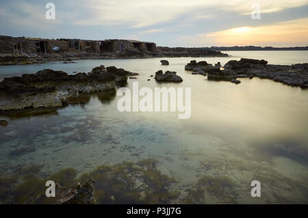 Tramonto dalla costa rocciosa di Ses Bassetes con barche tradizionali (parco naturale di Ses Salines, Formentera, Isole Baleari, Mar Mediterraneo, Spagna) Foto Stock