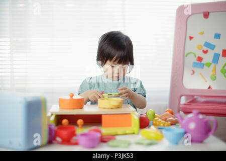 Baby girl fingere gioco giocattolo di cibo Foto Stock