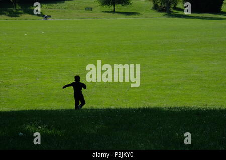 Silhouette di un bambino in esecuzione in un parco Foto Stock