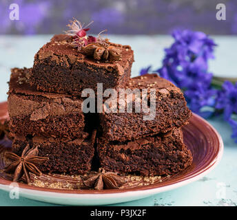 Pila di cotto quadrato pezzi di cioccolato Brownie la torta su un marrone piastra in ceramica, close up Foto Stock