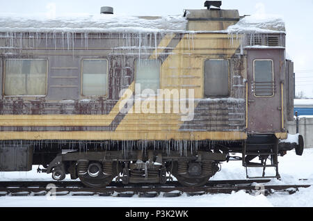 Foto dettagliate di una vettura congelate di treni passeggeri con ghiaccioli e ghiaccio sulla sua superficie. Stazione ferroviaria nella fredda stagione invernale Foto Stock