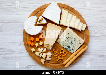 Degustazione formaggi deliziosi con noci, grissini e salatini su sfondo di legno, vista dall'alto. Cibo per romantico. Da sopra. Lay piatto. Foto Stock