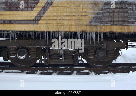 Foto dettagliate di una vettura congelate di treni passeggeri con ghiaccioli e ghiaccio sulla sua superficie. Stazione ferroviaria nella fredda stagione invernale Foto Stock