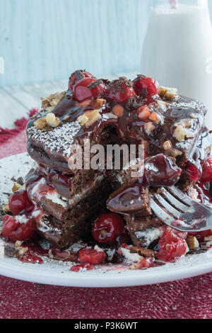 Deliziose frittelle di cioccolato - dessert gourmet per colazione? Primo piano di una pila di frittelle farcite con ciliegie, panna e noci. Varie angolazioni Foto Stock