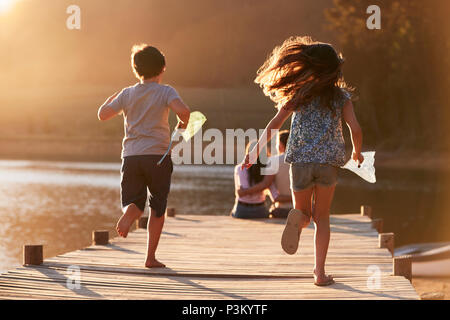 I bambini corrono verso i genitori sul pontile in legno sul Lago di Garda Foto Stock