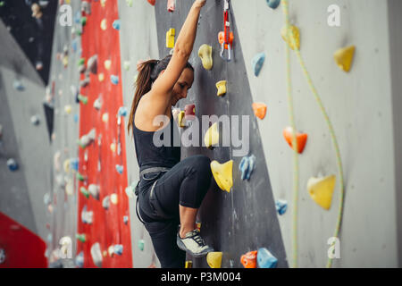 Sportivo da donna giovane la formazione in un colorato palestra di arrampicata. Foto Stock