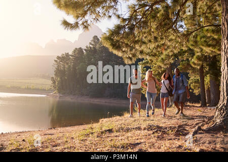 Un gruppo di giovani amici godendo a piedi dal lago su escursioni avventura Foto Stock