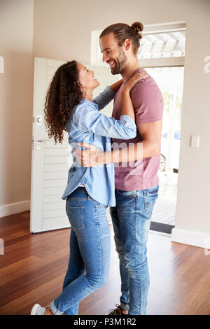 Eccitato giovane costeggiata dalla porta anteriore aperta nel salotto della nuova casa Foto Stock