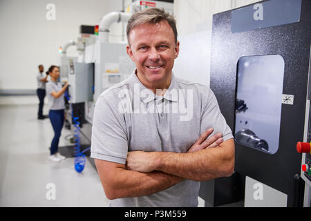 Ritratto di ingegnere maschio di funzionamento di macchine CNC in fabbrica Foto Stock