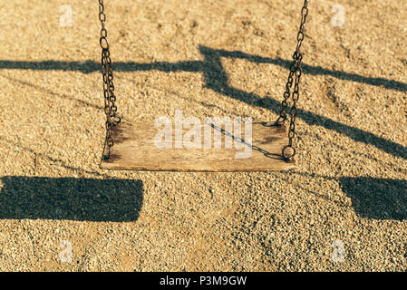 Vecchio abbandonato swing sul parco giochi per bambini al mattino Foto Stock