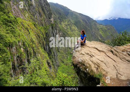 Giovane donna godendo la vista del Ponte di Inca e cliff percorso nei pressi di Machu Picchu in Perù. Il ponte è una parte di un sentiero di montagna che capi ad ovest di M Foto Stock