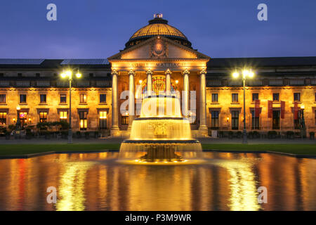 Kurhaus e Bowling Green in serata con luci, Wiesbaden, Hesse, Germania. Wiesbaden è uno dei più antichi centri termali in Europa Foto Stock