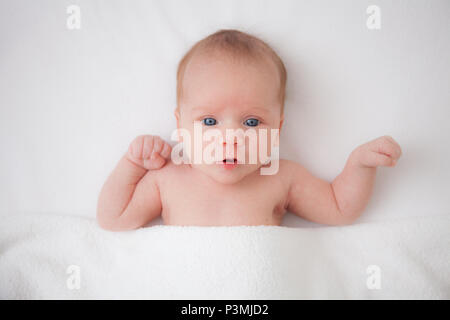 Carino adorabile neonato ragazza nel letto bianco e guardando la telecamera Foto Stock