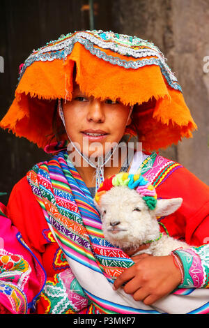 Giovane donna in abito tradizionale azienda agnello in strada di Cusco, Perù. Nel 1983 Cusco è stata dichiarata dall Unesco patrimonio dell umanità Foto Stock