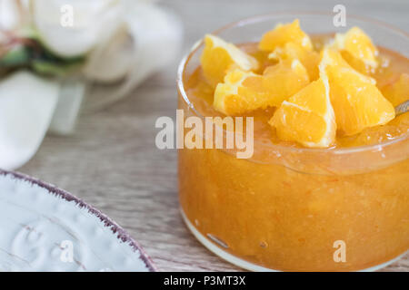 Inceppamento arancione in recipiente di vetro con arancia fresco affettato sulla parte superiore Foto Stock