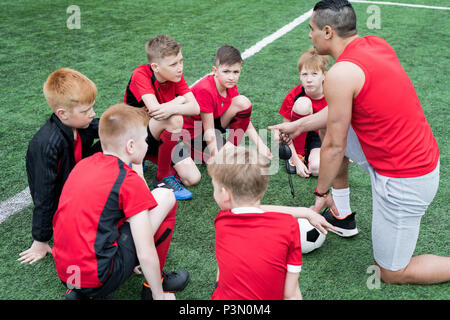 Bambini ascolto di Pep parlare prima del gioco Foto Stock