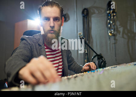 Produttore barbuto lavorando presso la console in studio Foto Stock