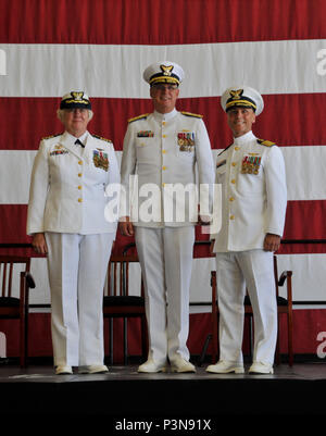 Il cap. Keith cavalcavia (destra) alleviato Capt. Patricia McFetridge (sinistra) come il comandante della stazione di aria Borinquen durante un cambio del comando cerimonia presieduta da Adm posteriore. Scott Buschman (centro), Coast Guard settimo distretto, comandante della base aeromobili hangar Luglio 8, 2016 in Aguadilla, Puerto Rico. Stazione aria Borinquen personale, insieme con il gruppo di quattro MH-65D Dolphin elicotteri, condurre operazioni di ricerca e salvataggio, l'applicazione della legge, Homeland security, marine la tutela ambientale, alieno di interdizione del migrante e counterdrug delle missioni in tutta l'area caraibica orientale di responsa Foto Stock