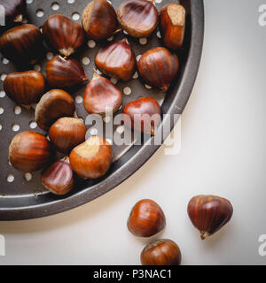 Vista superiore del le castagne in un tegame su uno sfondo bianco. Formato quadrato. Foto Stock