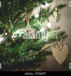 Vista ravvicinata di un albero di Natale decorato con la stella di legno a forma di cuore decorazioni. Concetto di vacanza. Formato quadrato. Foto Stock